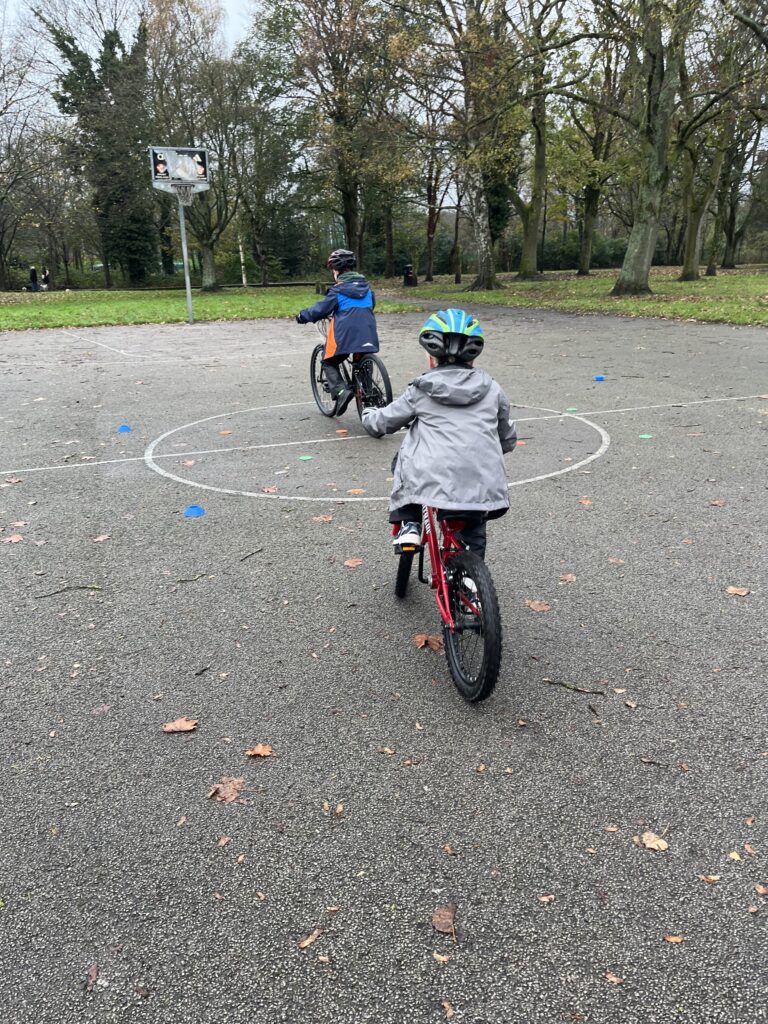 Two Children learning to ride bicycles playing a game involving cones