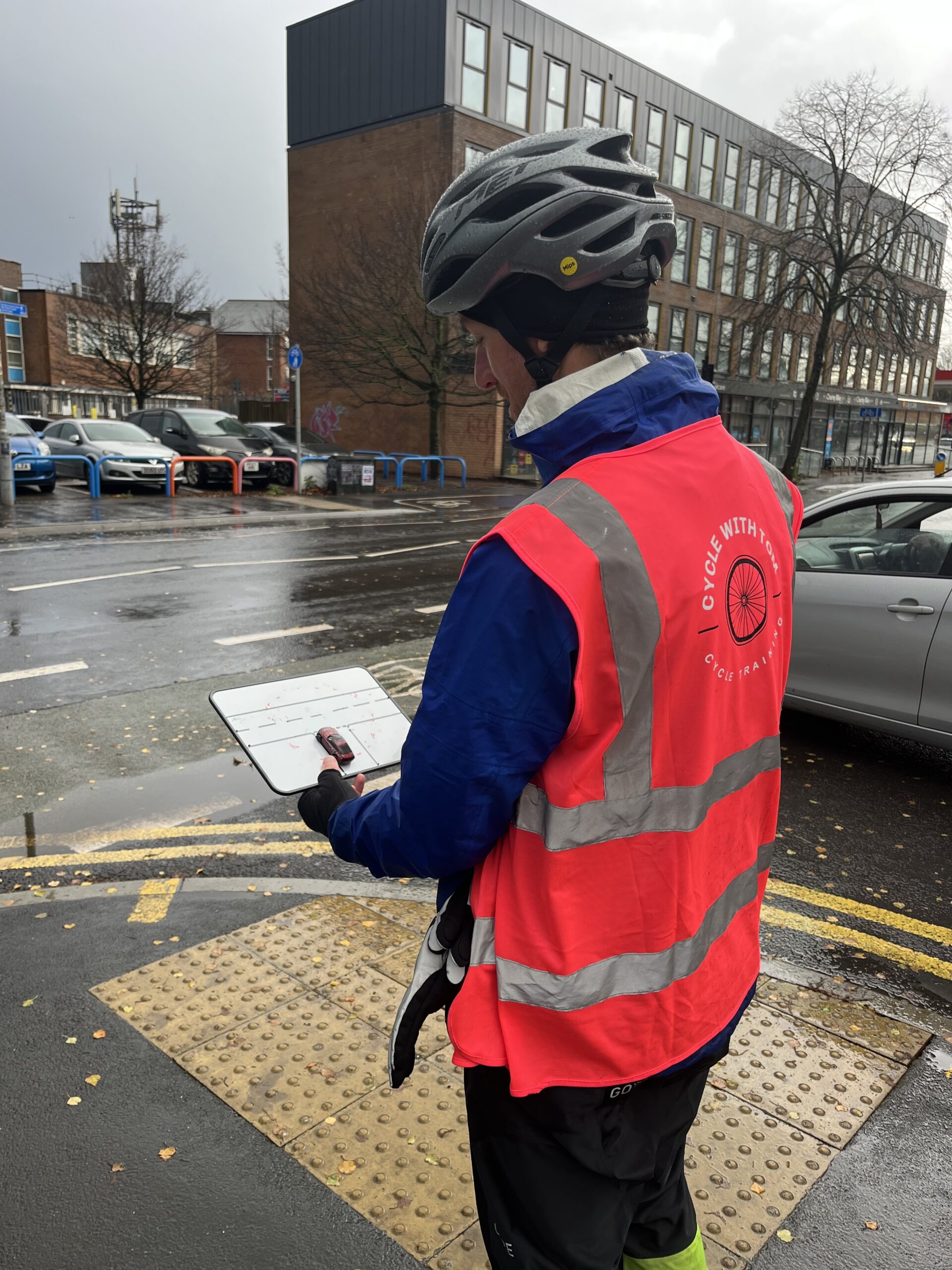A man with a whiteboard standing next to a road junction